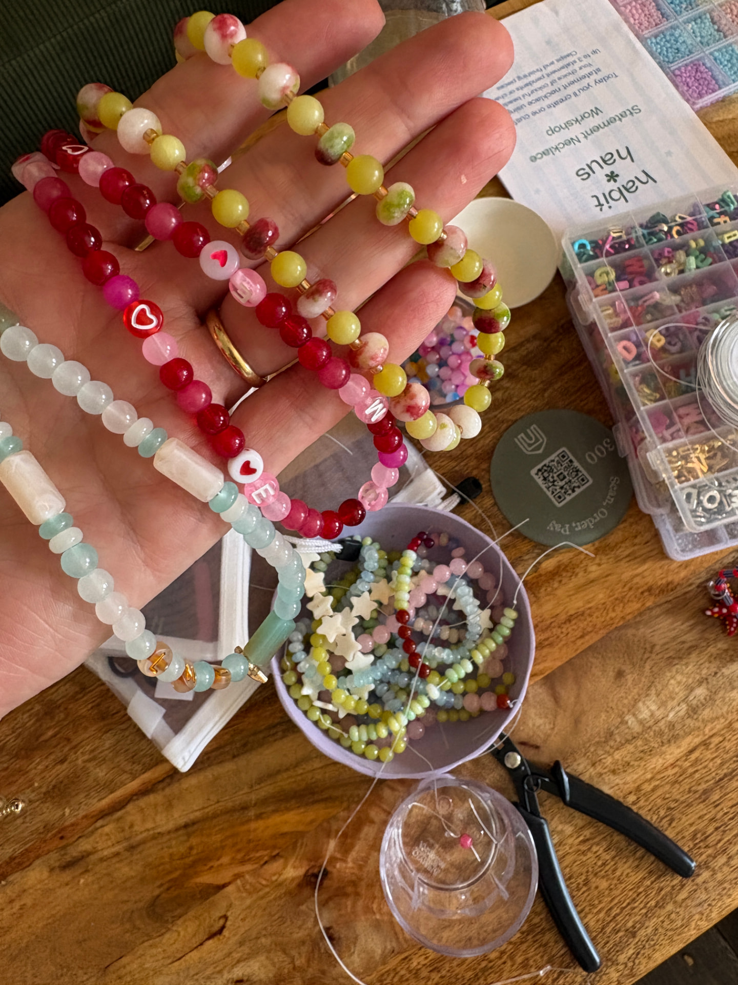 Close-up of a red, pink and green beaded necklace with a gold sun charm